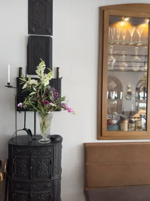 Historischer gusseiserner Ofen mit frischem Blumenschmuck in der Drachenburg Marktbreit, Blick auf die Weinauswahl.